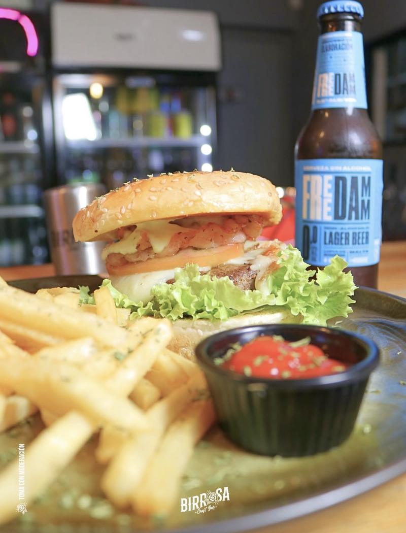 Hamburguesa con papas fritas junto a una botella de Freedamm 0.0